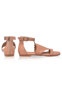 A pair of women's flat sandals in a warm tan or nude color, featuring a side zipper on one sandal, a buckle strap on the other, and laser-cut scalloped and perforated details on the toe strap, shown against a plain white background.
