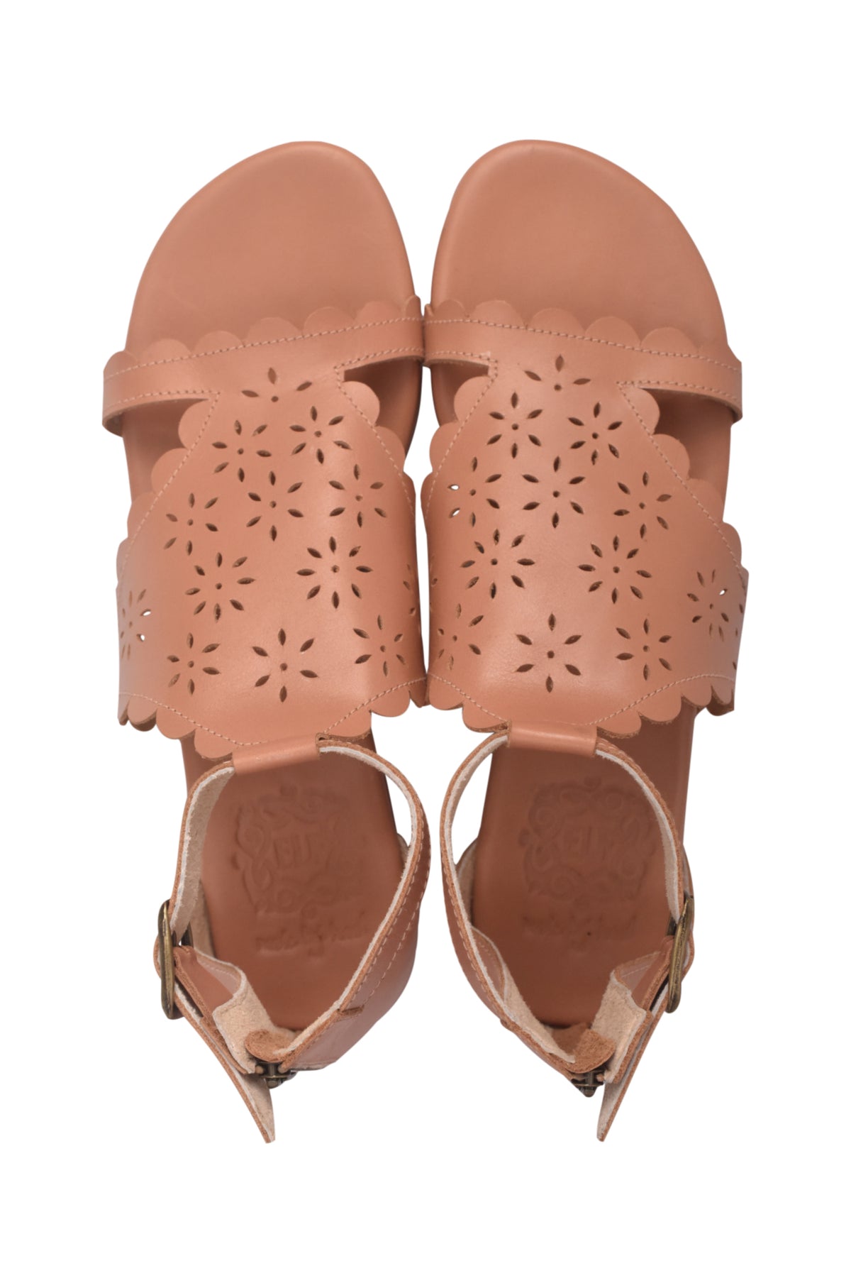 A pair of women's flat sandals in a warm tan or nude color, featuring scalloped edges and laser-cut floral patterns on the straps, shown from a top-down view on a white background.