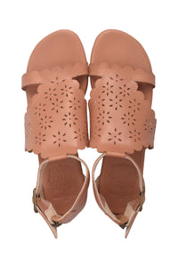 A pair of women's flat sandals in a warm tan or nude color, featuring scalloped edges and laser-cut floral patterns on the straps, shown from a top-down view on a white background.