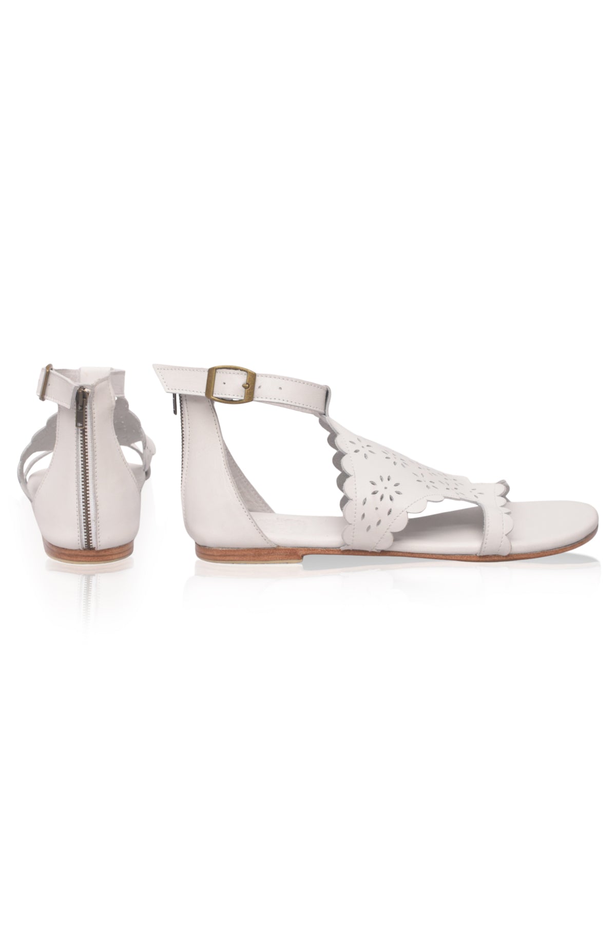 A pair of women's flat sandals in off-white leather, featuring laser-cut floral details on the toe strap, a side zipper, and an adjustable ankle buckle with a gold-tone metal accent.