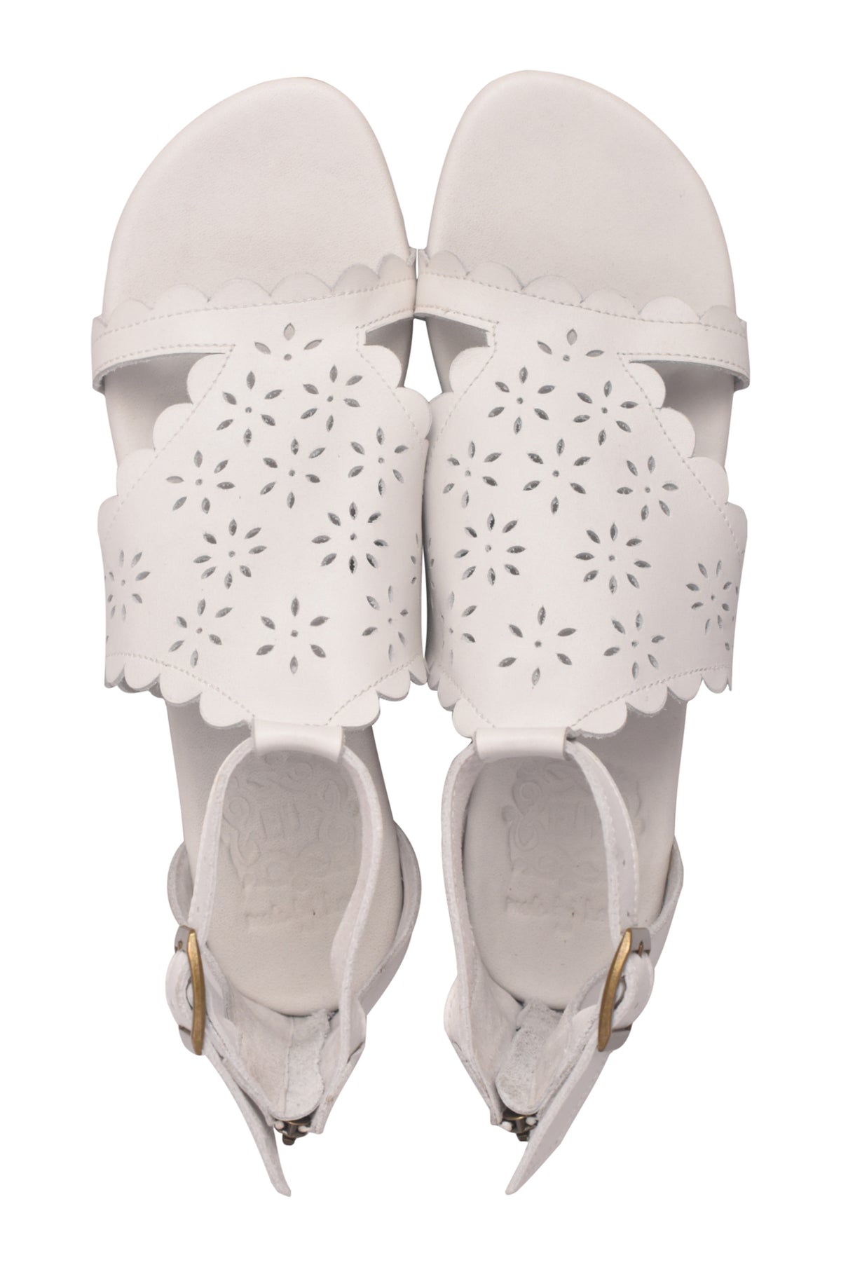 A pair of white leather sandals with scalloped edges and laser-cut floral patterns on the straps, shown from a top-down view on a white background.