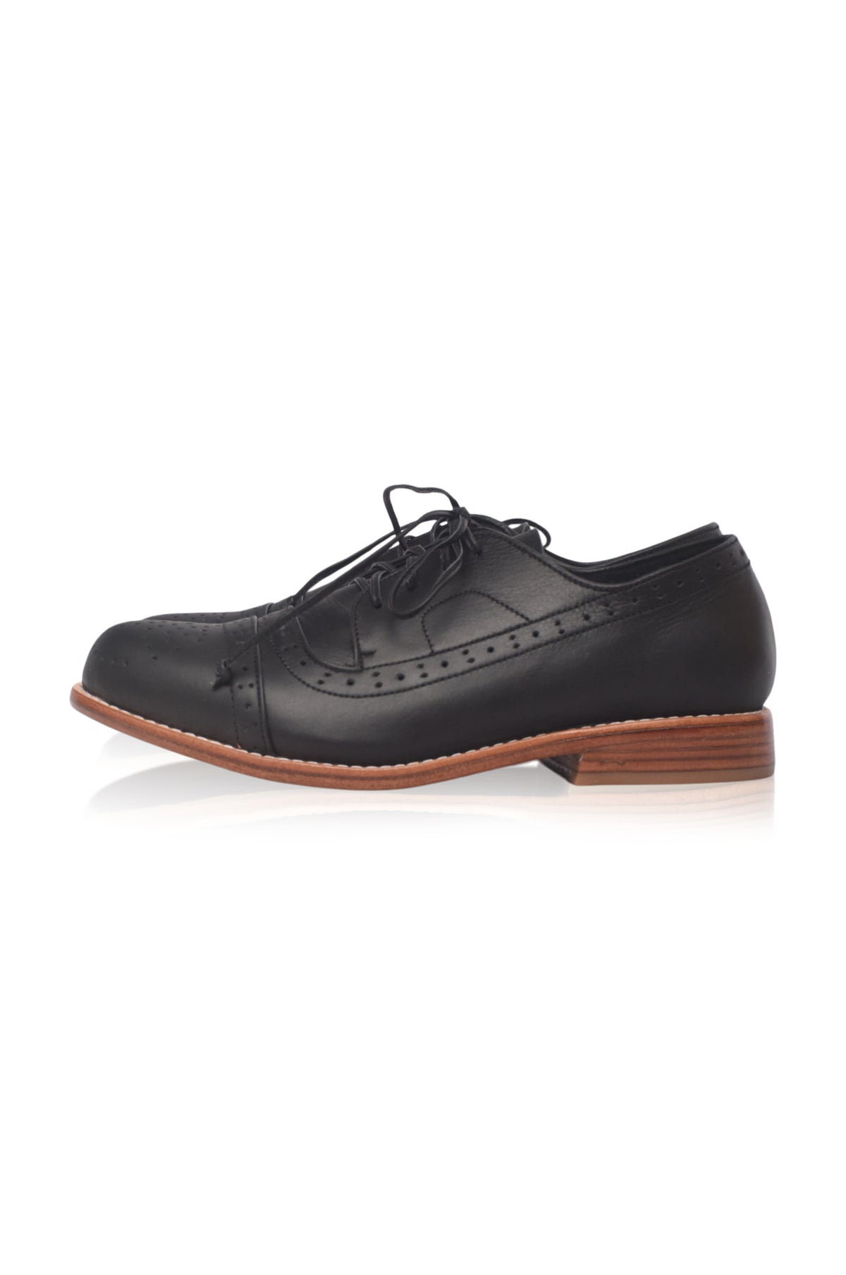 A single black leather wingtip oxford shoe with decorative brogue perforations, black laces, and a stacked brown wood-look heel, shown from a side profile on a white background.