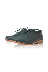 A pair of dark green leather lace-up shoes with a low stacked heel and light brown sole, shown on a white background with a soft reflection.