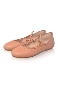 A pair of women's ballet flats in a dusty peach-beige color, featuring criss-crossing lace-up straps across the instep, shown on a plain white background.