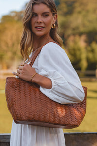 Woman holding a brown woven handbag outdoors