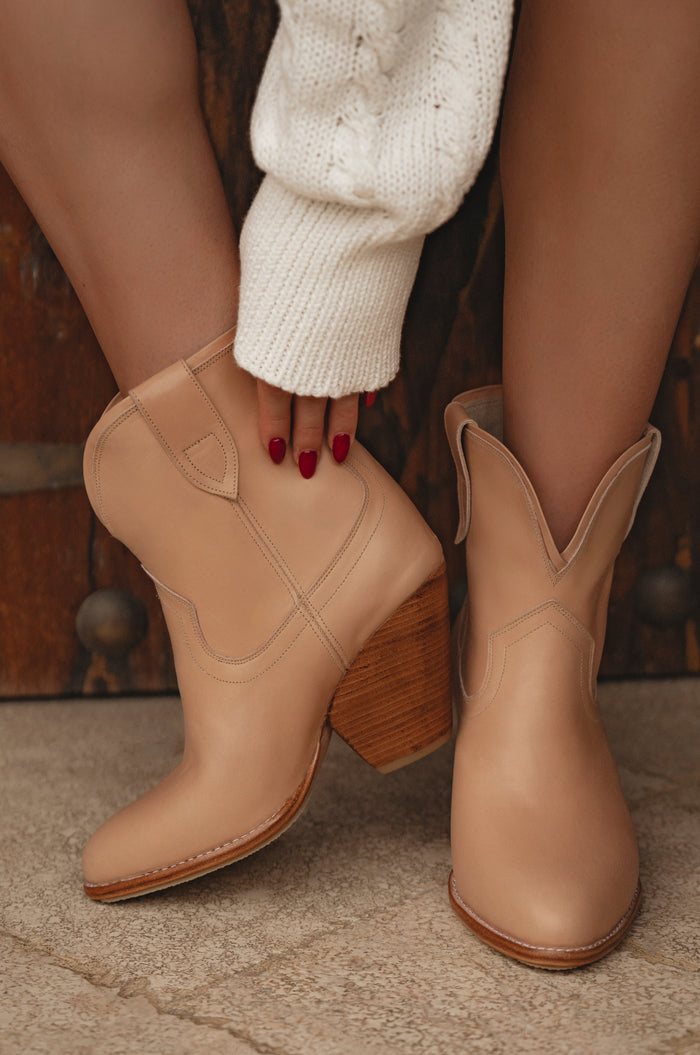 Tan cowboy boots with wooden heel on a neutral background