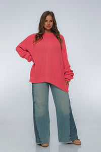 Woman wearing a pink sweater and blue jeans on a white background
