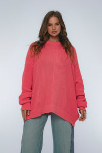 Woman wearing a pink sweater and gray pants on a white background