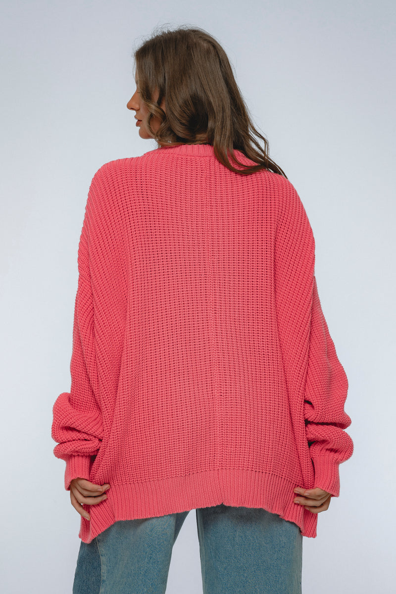 Person wearing a pink sweater on a plain background