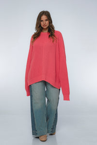Woman wearing a pink sweater and blue jeans on a white background