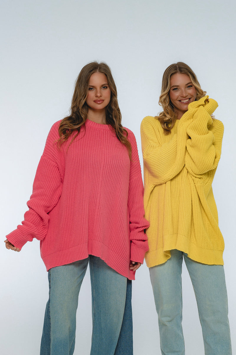 Two women wearing oversized sweaters, one pink and one yellow, on a white background.