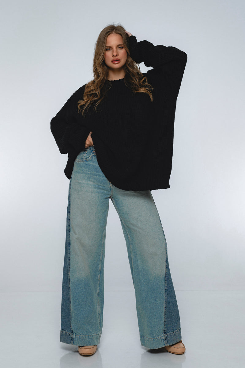 Woman wearing a black sweater and light blue jeans on a white background