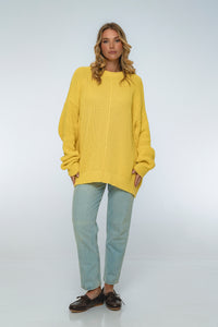 Woman wearing a yellow sweater and light blue jeans on a white background