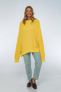 Woman wearing a yellow sweater and light blue jeans on a white background