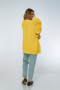 Person wearing a yellow sweater and light blue pants on a white background