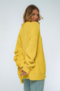 Woman wearing a yellow oversized sweater on a plain background