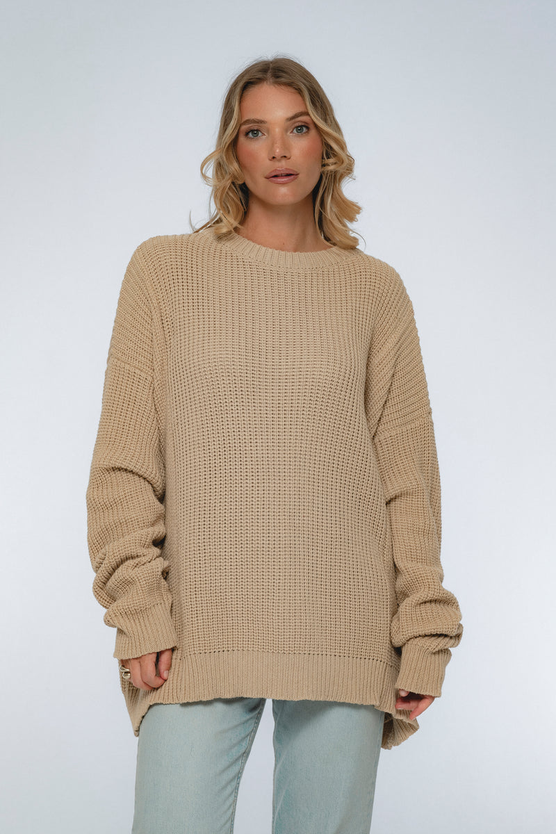 Woman wearing a beige sweater against a white background