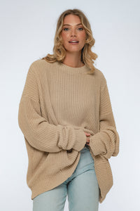 Woman wearing a beige knitted sweater on a white background