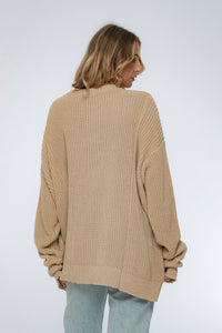 Woman wearing a beige knitted sweater on a white background