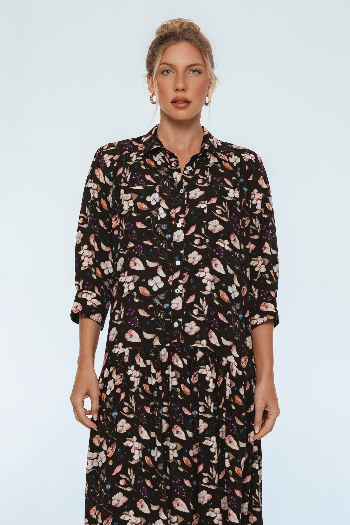 Woman wearing a black floral dress against a plain background