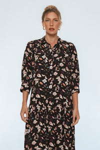 Woman wearing a black floral dress against a plain background