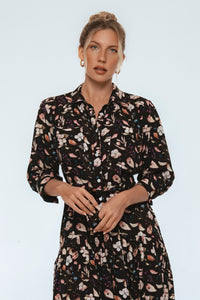 Woman wearing a black floral dress against a light blue background