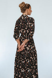 Woman wearing a black floral dress against a white background