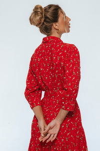 Woman wearing a red dress with a subtle pattern on a light gray background