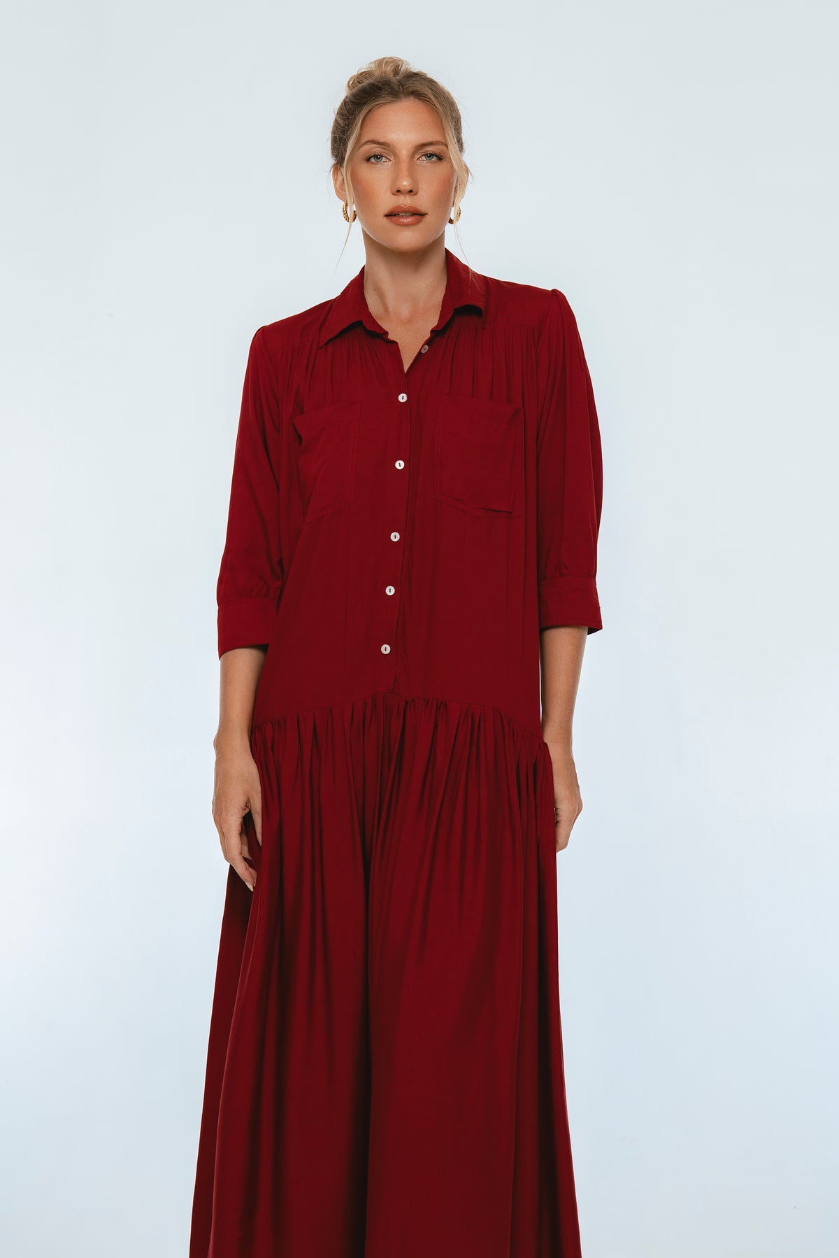 Woman wearing a long burgundy dress against a white background