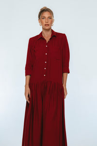 Woman wearing a long burgundy dress against a white background