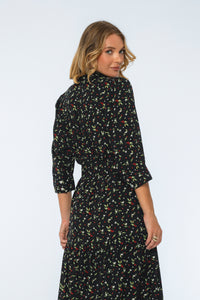 Woman wearing a black floral dress against a white background