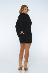 Woman wearing a black sweater dress with beige boots on a white background