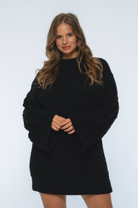 Woman wearing a black sweater dress against a white background