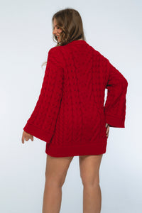 Person wearing a red cable knit sweater on a white background