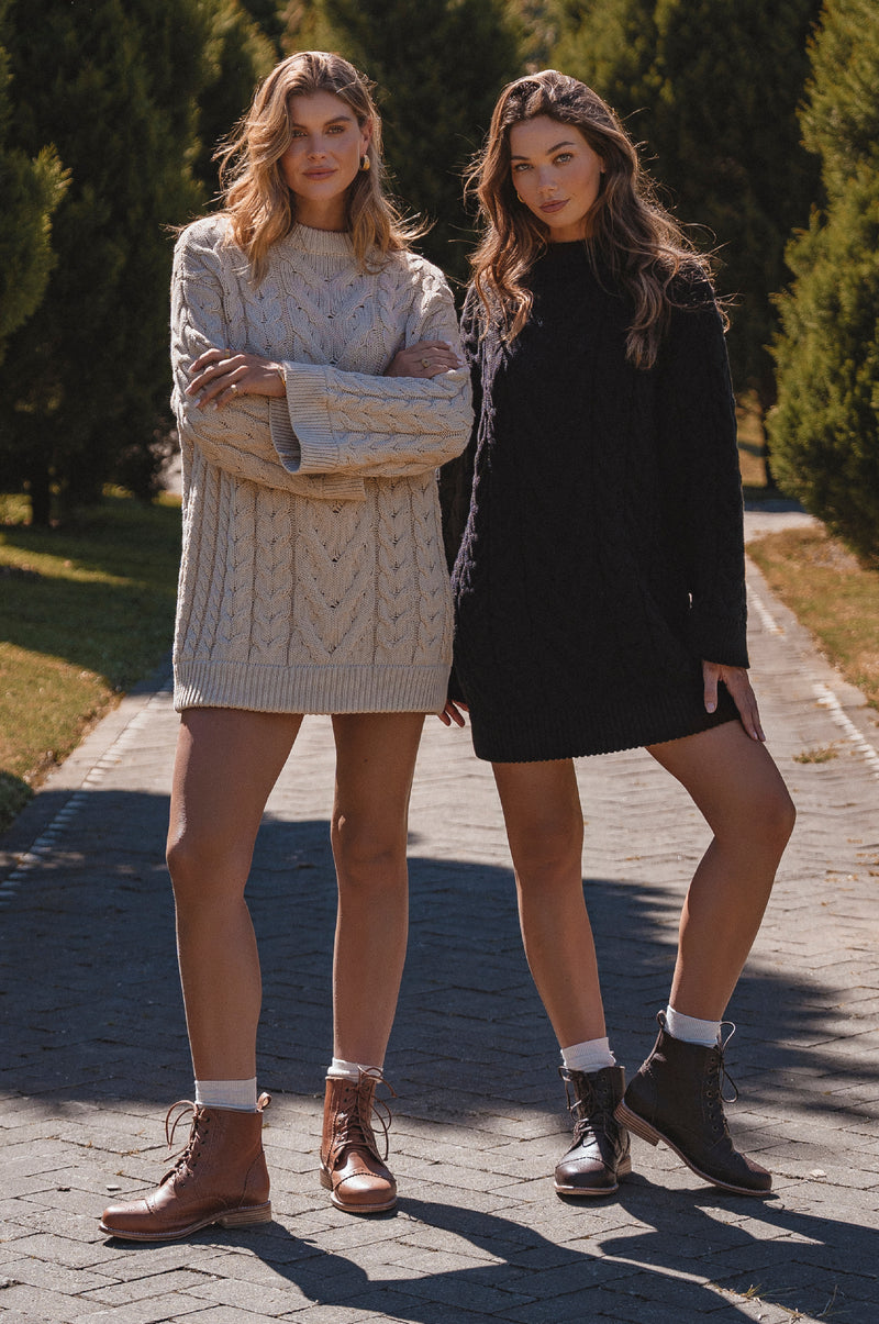 Two women standing on a paved path with trees in the background