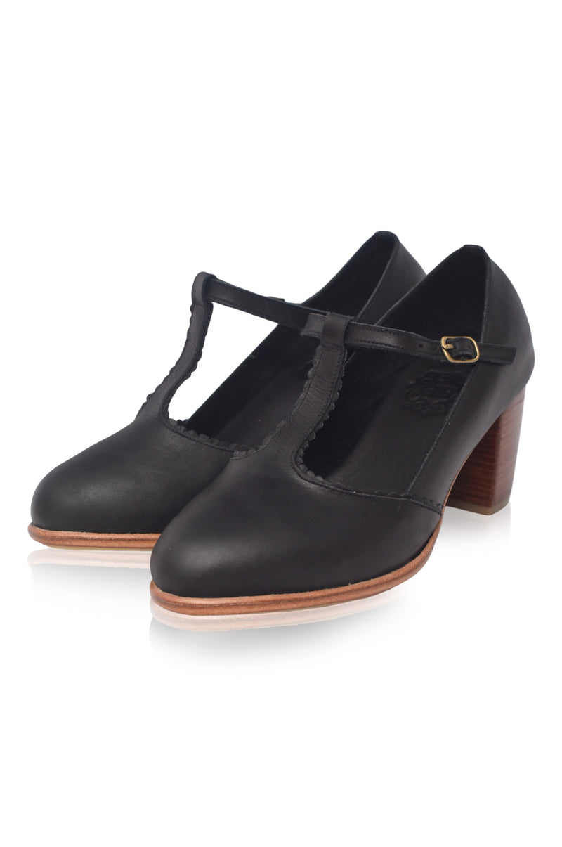Black leather shoes with a T-strap design on a white background