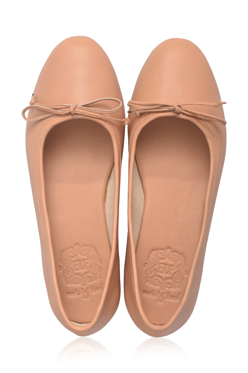 Pair of tan flat shoes with bow details on a white background
