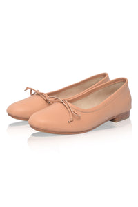 Pair of peach-colored ballet flats with a bow on a white background