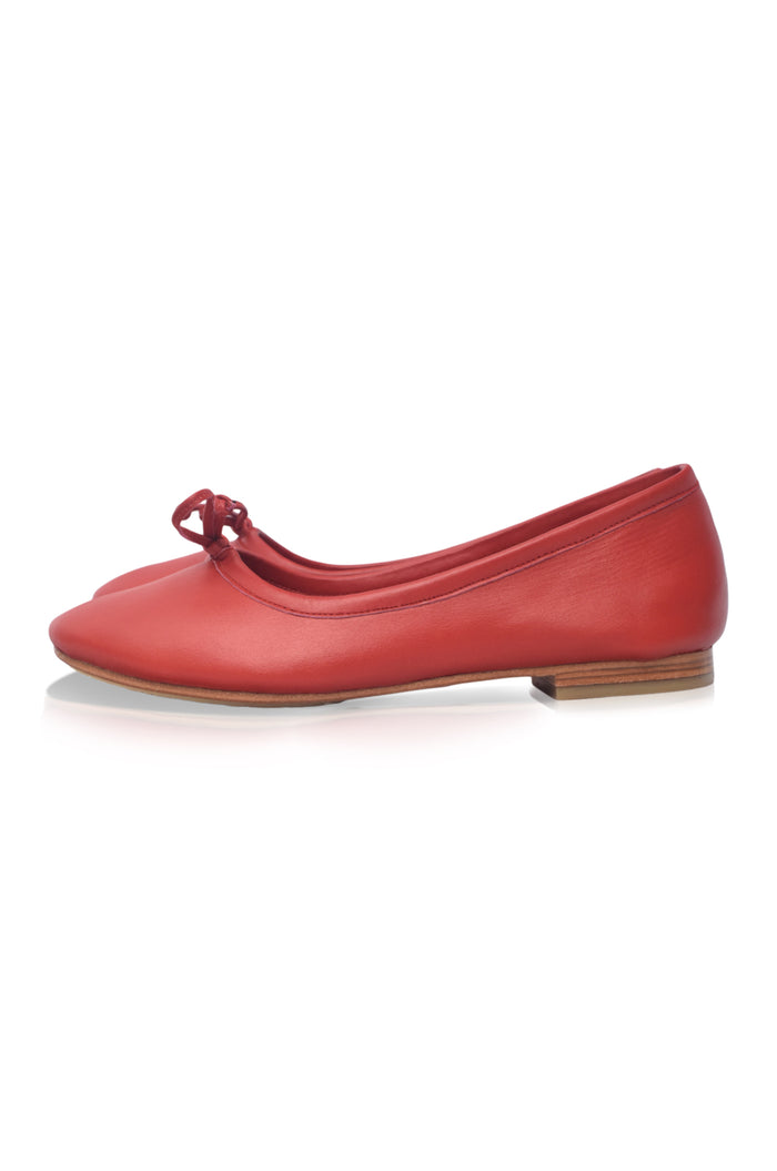 Red flat shoe with a bow on a white background
