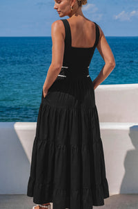 Woman wearing a black dress with a white wall and blue ocean in the background