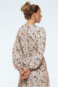 Woman wearing a floral dress with long sleeves on a white background
