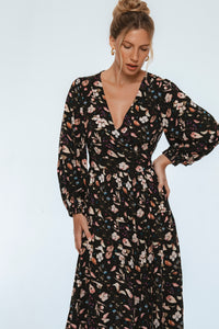 Woman wearing a black floral dress against a light gray background