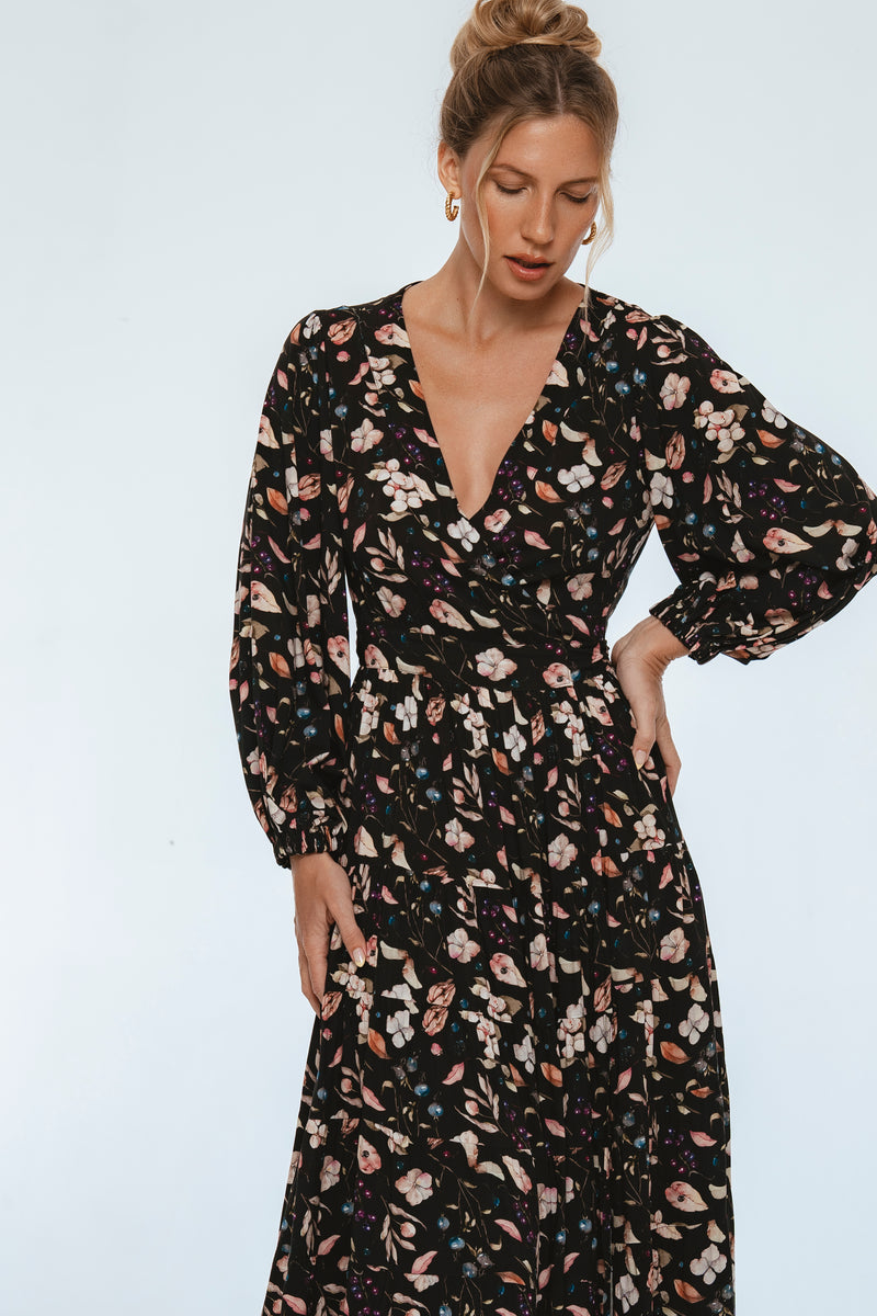 Woman wearing a black floral dress against a light gray background