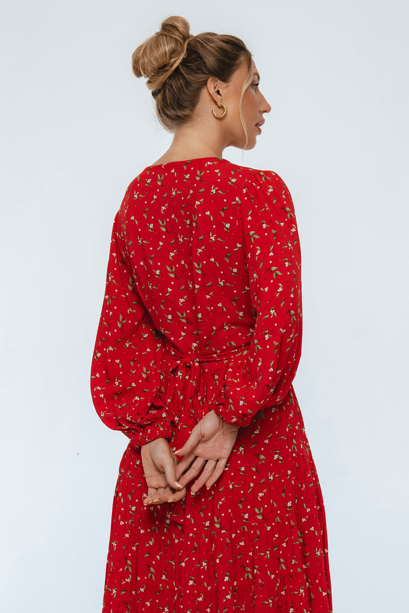 Woman wearing a red dress with a subtle pattern on a light gray background