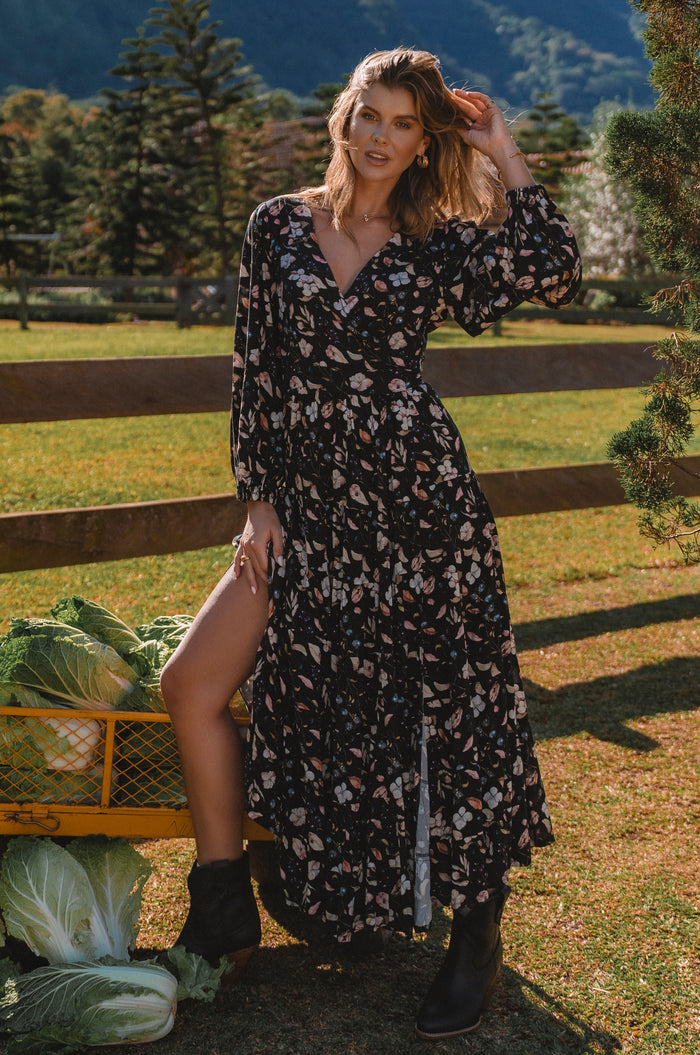Woman in a floral dress standing outdoors with a scenic background