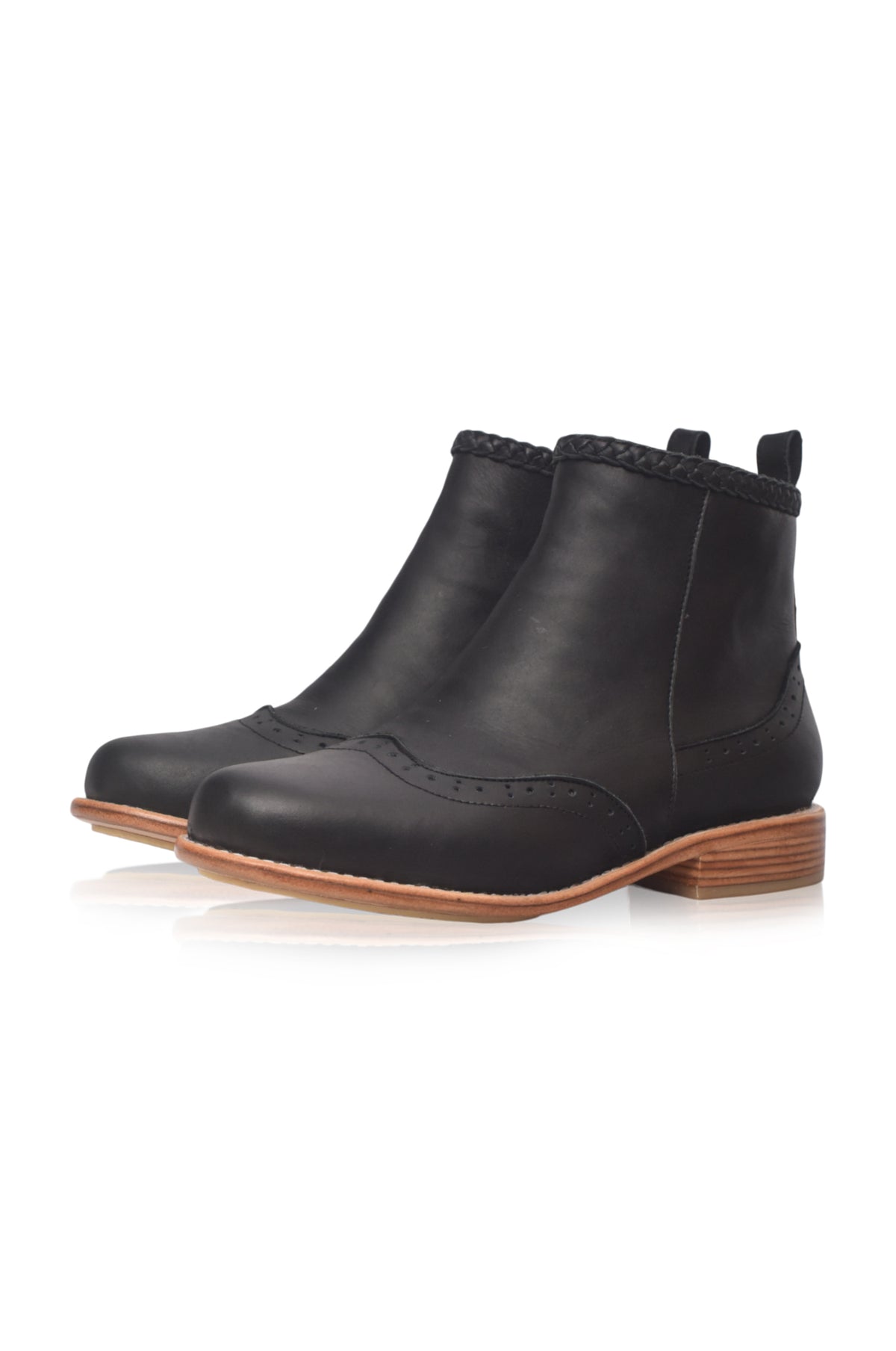 A pair of black leather ankle boots with a low stacked wood-look heel, brogue detailing, and a braided trim at the collar, shown on a white background.