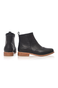 A pair of black leather ankle boots with wingtip detailing and stacked brown wooden heels, shown from the side and back on a white background.