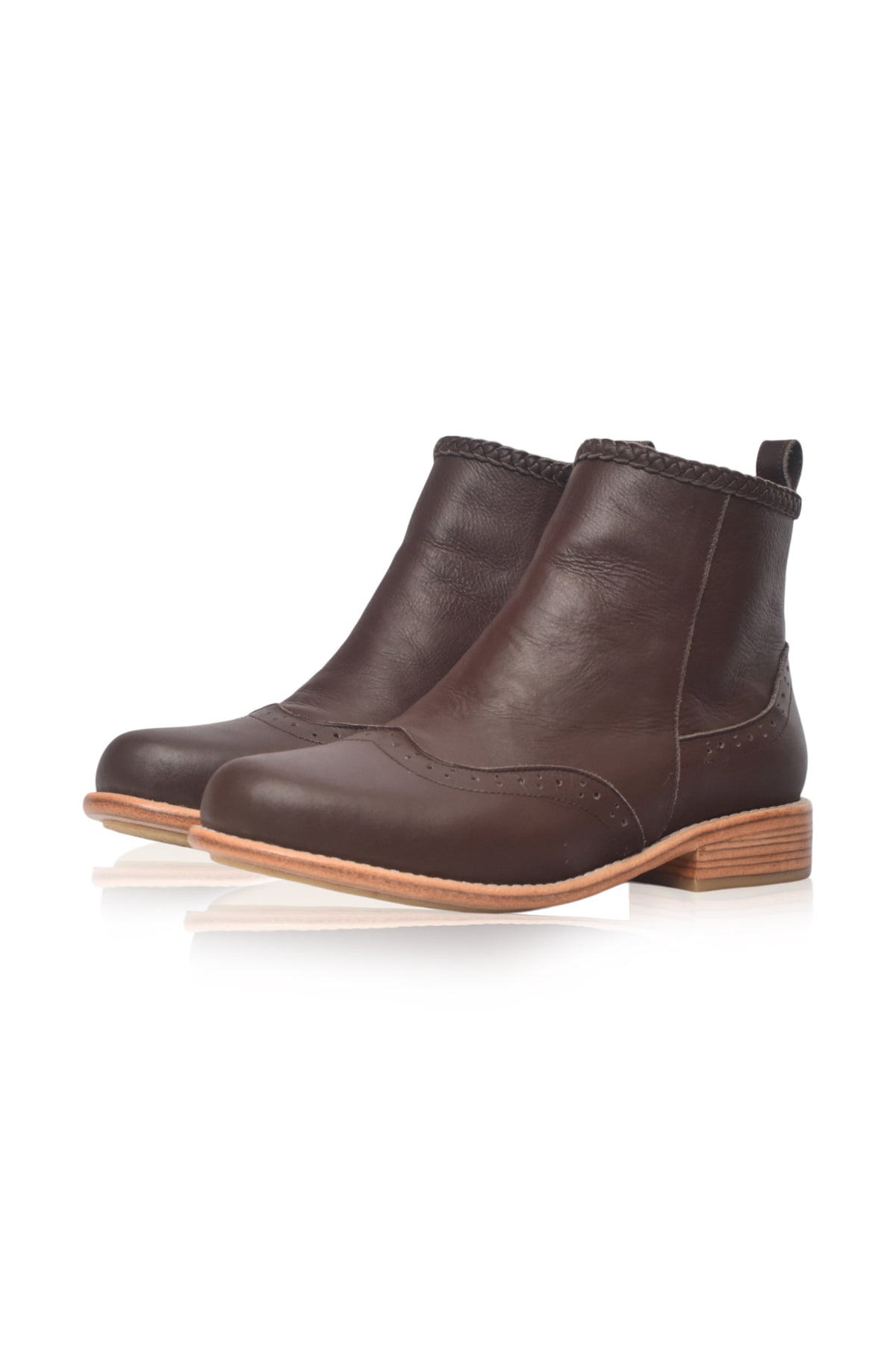 A pair of dark brown leather ankle boots with a low stacked heel and a light tan sole, shown on a clean white background with a soft reflection.