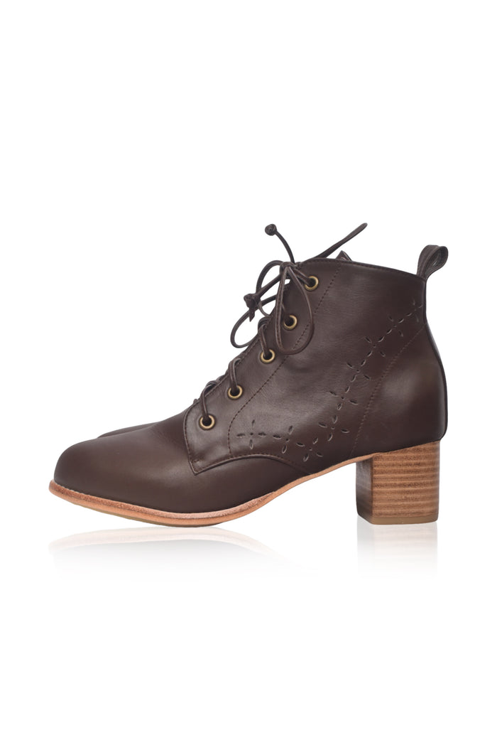 A dark brown leather lace-up ankle boot with a stacked wooden block heel and brass eyelets, shown from a side profile on a white background.