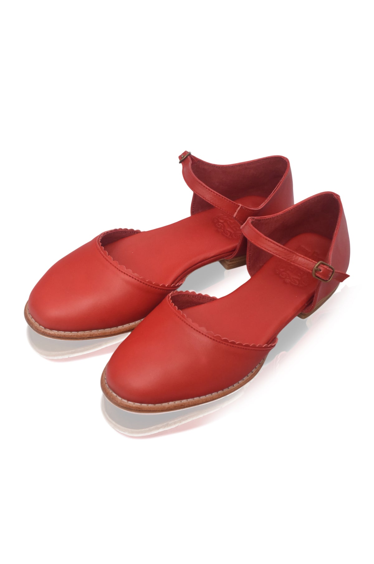 A pair of red leather Mary Jane style shoes with low block heels and ankle straps, displayed on a clean white background.